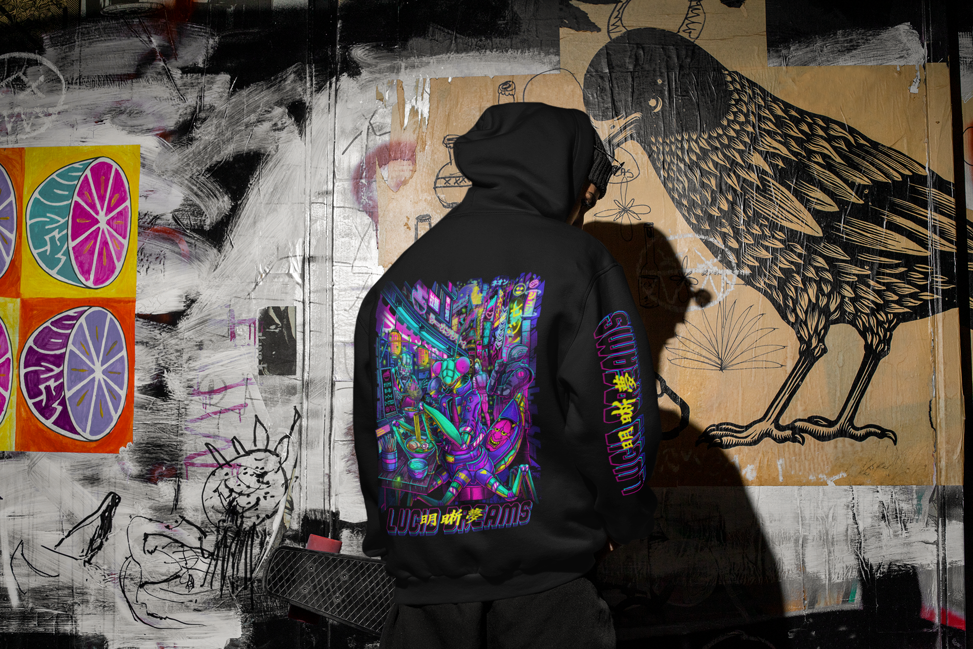 Person wearing a hoodie with colorful designs in front of a graffiti-covered wall.