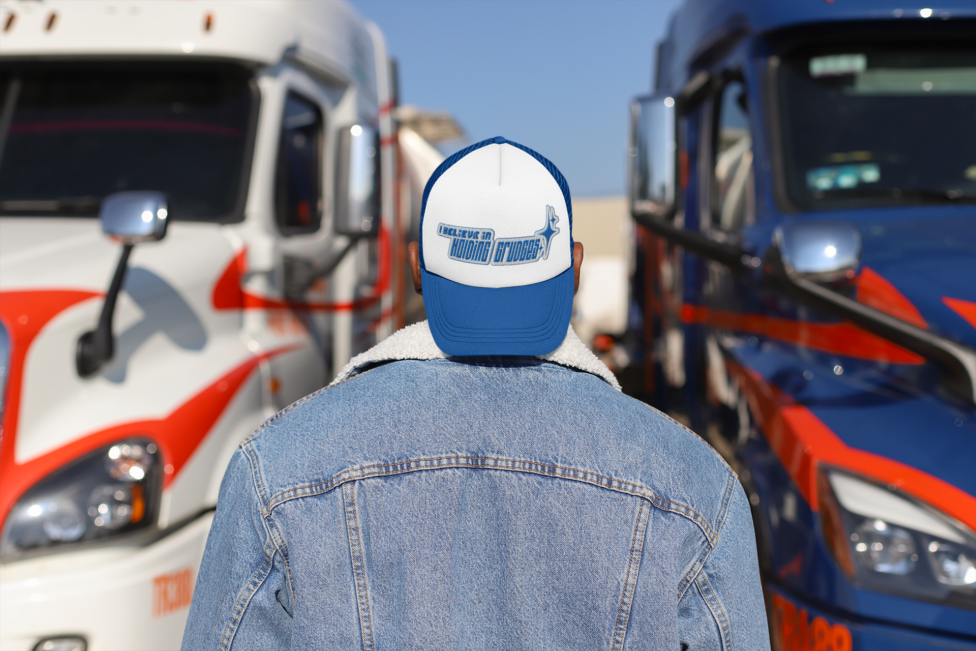 Person wearing a cap with a logo in front of two trucks